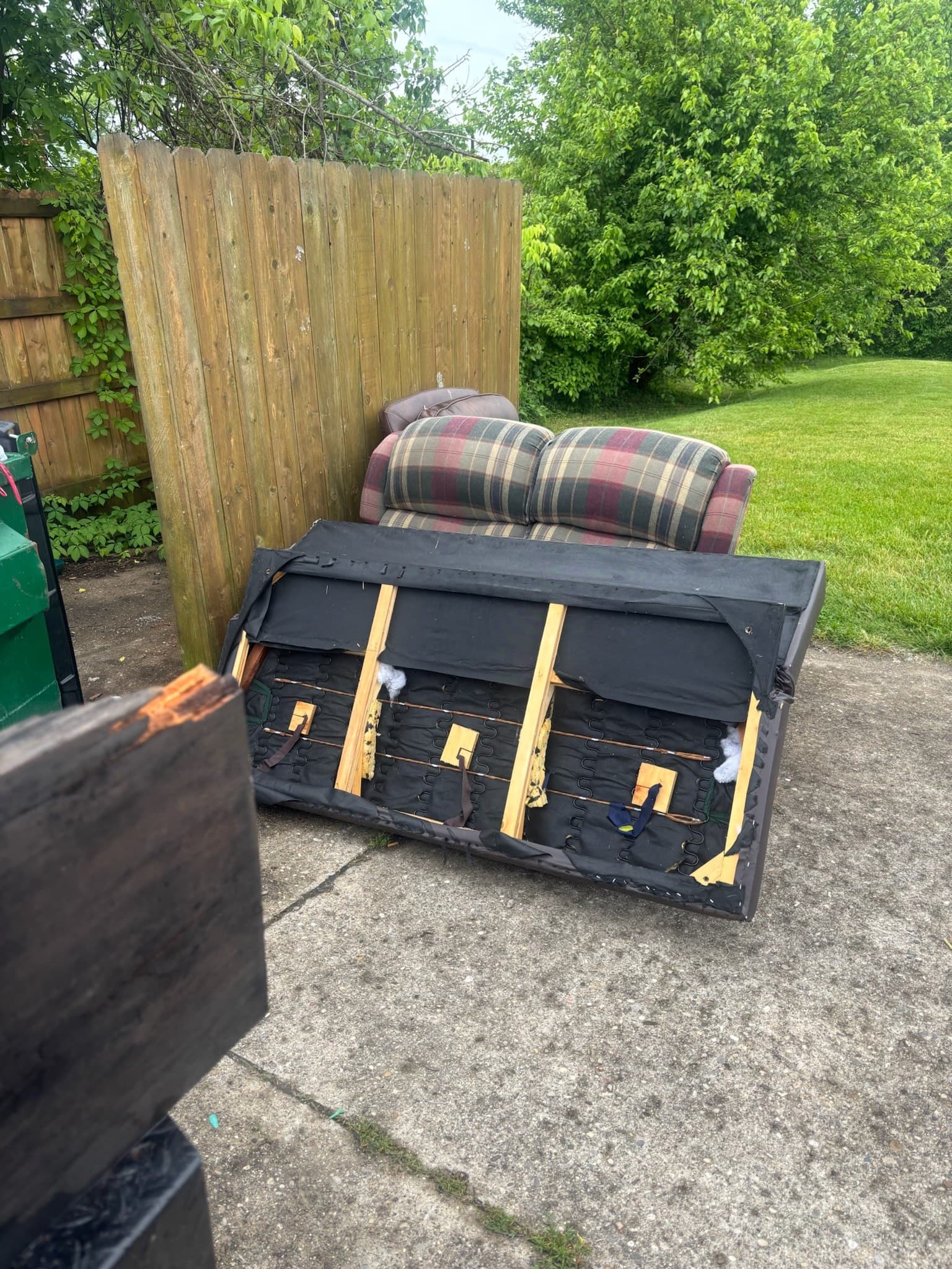 Couch and recliner beside an apartment fence before removal