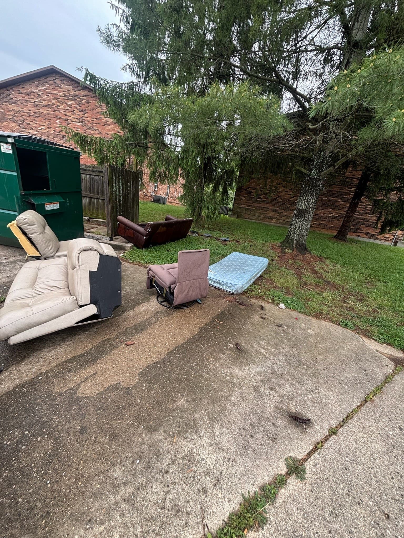 Discarded furniture near an apartment dumpster before cleanup