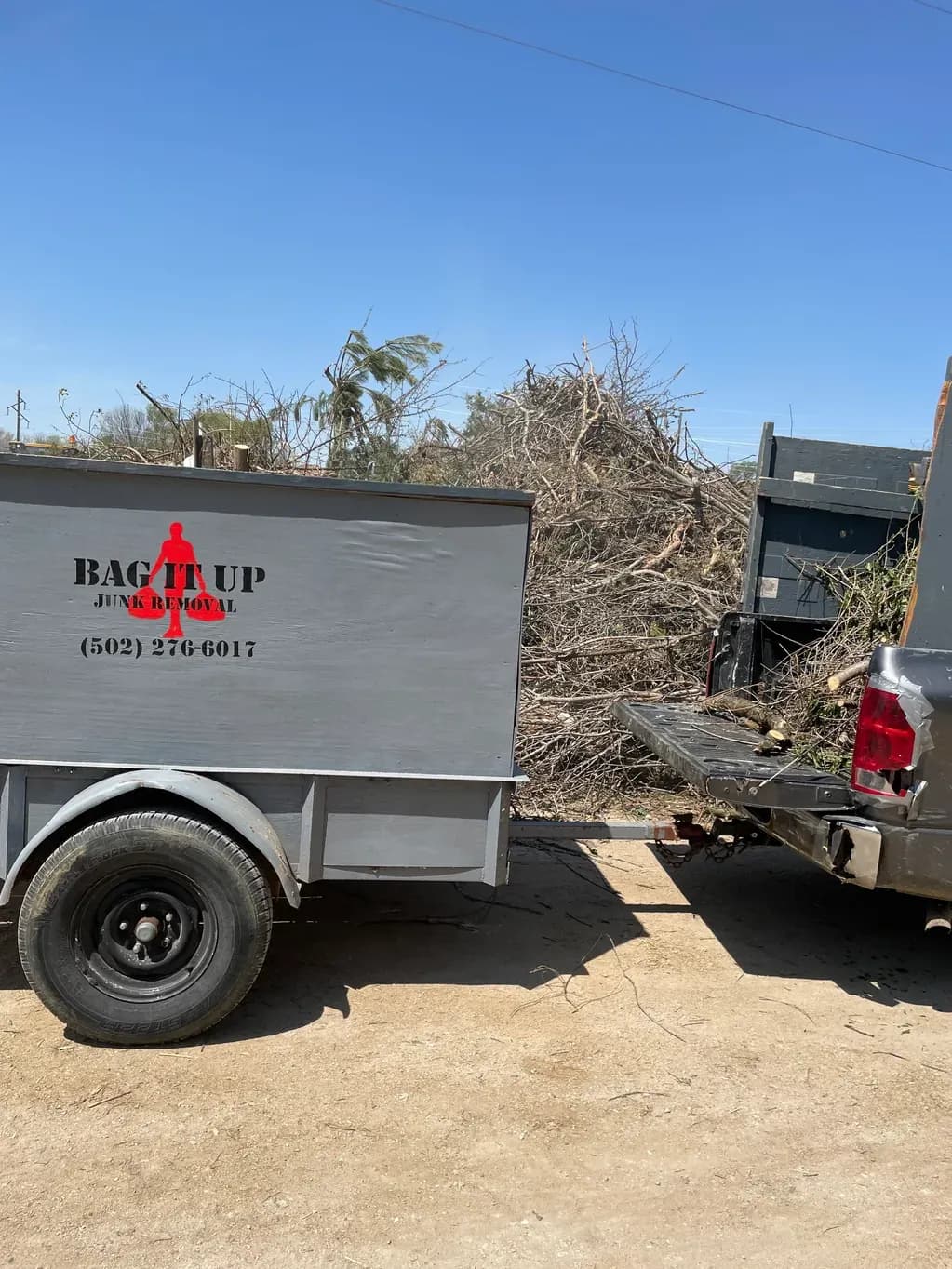 Bag It Up junk removal trailer loaded with yard debris at a Louisville job site