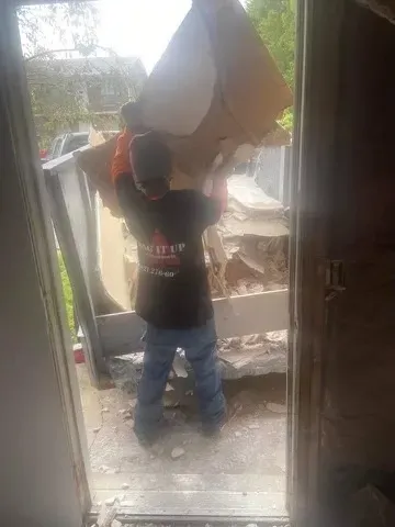Bag It Up crew member hauling debris from a Louisville job site